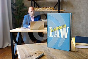 Lawyer holds LABOUR LAW book. Labour lawÃÂ mediates the relationship between workers, employing entities, trade unions and the photo